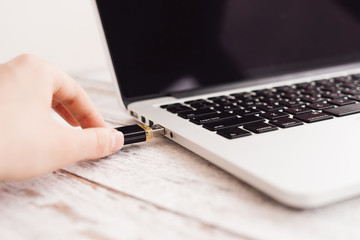 Woman hand entering inserting usb flash into laptop computer
