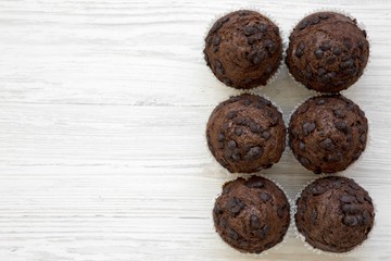 Chocolate cupcakes on white wooden background, top view. Flat lay, overhead, from above. Copy space.
