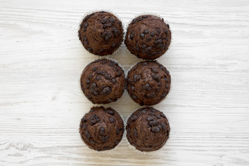 Chocolate muffins on white wooden background, overhead view. Flat lay, top view, from above.