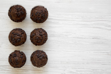 Chocolate muffins on white wooden background, overhead view. Flat lay, top view, from above. Copy space.