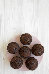 Chocolate muffins on pink plate on white wooden table, top view. Flat lay, overhead, from above. Space for text.