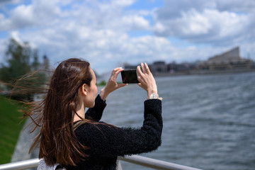 young woman on the waterfront taking pictures of the city landscape