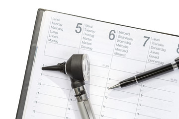 Doctor Agenda. Otoscope and pen lyinhg on agenda after exam