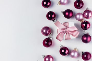 Christmas flat lay scene with pink abd violet glass balls and gift box with copy space on white