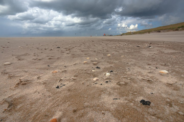 Steep sand in strong winds along the beach with threatening clouds.