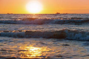 Obraz premium Sunset over the sea. Reflection of sunlight in the sea waves. Red sky in the rays of the sunset.