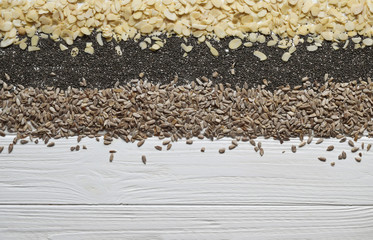 Chia seeds, almond petals and sunflower seeds on a white wooden background. Top view. Copy space.