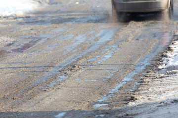 the car drives on wet and dirty asphalt on a winter road