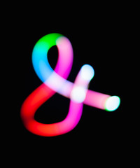 Glowing ampersand symbol & logogram on dark background. Abstract night light painting. Creative...