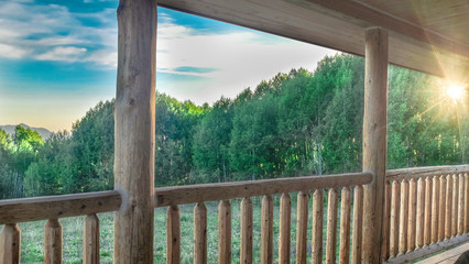 rustic log balcony, striped bark of aspen trees, looking out at aspen forest and field