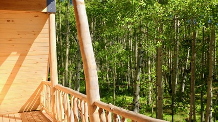 rustic balcony built of raw wood logs, looking out at aspen tree forest