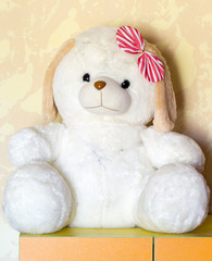 sits a furry toy white dog