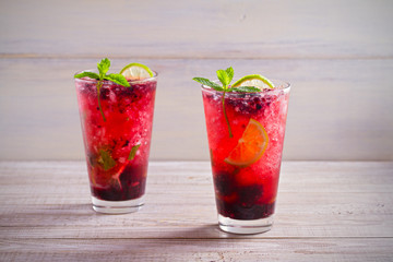Blackberry mojito cocktail with berries, lime and mint on wooden background. horizontal