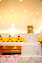 Figurines of the bride and groom on a wedding cake.Funny figurines suite at a luxury wedding white cake decorated .Figurines on top of wedding cake with roses decorations.