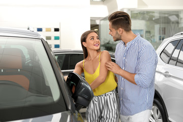 Young couple choosing new car in salon