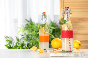 Bottles with natural lemonade on table against blurred background