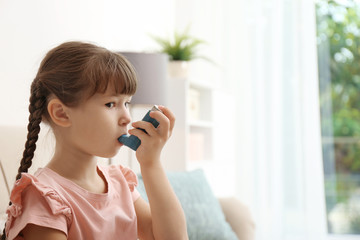 Little girl using asthma inhaler on blurred background - obrazy, fototapety, plakaty