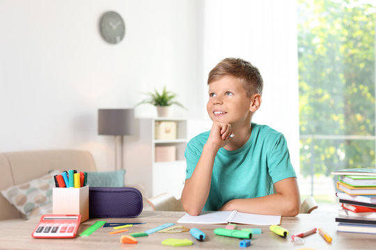 Little boy daydreaming while doing assignment at home. Stationery for school - Powered by Adobe