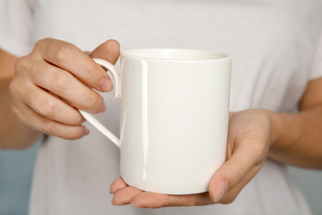 Fototapeta na wymiar Woman holding ceramic cup, closeup. Mock up for design