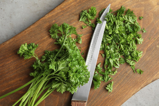 Wooden board with fresh green parsley and knife on table, top view