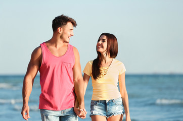 Happy young couple walking together on beach