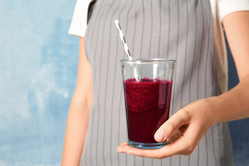 Woman with glass of beet smoothie on color background, closeup
