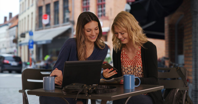 Two Lost Girls Using Smartphone Laptop To Locate Destination In Bruges, Belgium