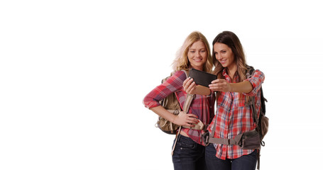 Portrait of two pretty backpacking females taking selfie on white copy space