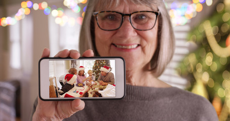 Happy grandma showing smartphone video of her with family on Christmas