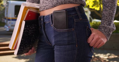 College girl with books and phone in pocket on campus after getting off bus