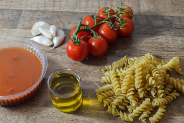 Raw pasta and ingredients (noodle, cherry tomatoes, olive oil, garlic) for make traditional italian food.