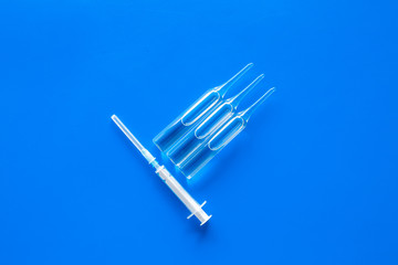 Flu vaccination concept. Syringe and ampoulie on blue background top view copy space
