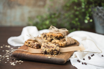 Homemade Chewy Granola Bars Wrapped in Parchment Paper and String on a Wood Cutting Board on Wood Table