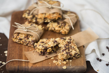Homemade Chewy Granola Bars Wrapped in Parchment Paper and String on a Wood Cutting Board on Wood Table