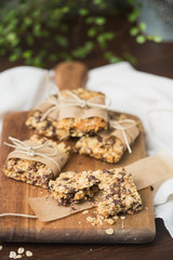 Homemade Chewy Granola Bars Wrapped in Parchment Paper and String on a Wood Cutting Board on Wood Table