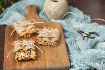 Homemade Chewy Granola Bars Wrapped in Parchment Paper and String on a Wood Cutting Board on Wood Table