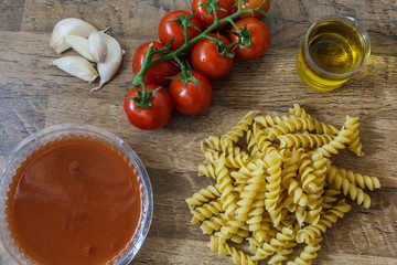 Raw pasta and ingredients (noodle, cherry tomatoes, olive oil, garlic) for make traditional italian food.