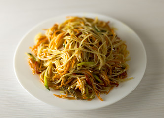 Rice noodles Funchoza with vegetables in a white plate. Traditional Korean cuisine