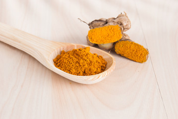 Turmeric powder and fresh turmeric on wooden background.