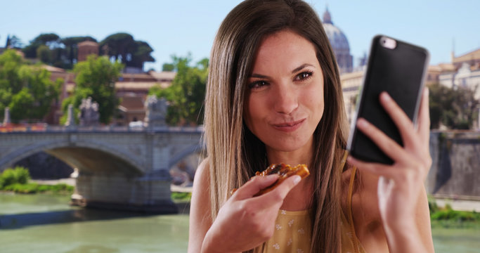 Pretty woman taking selfie photo and eating slice of pizza outside in Rome