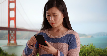 Close up of cute woman using cell phone and sending texts in San Francisco