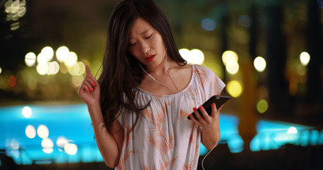 Joyful millennial listening to music with smartphone at recreation center