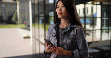 Joyful millennial listening to music with smartphone at university campus