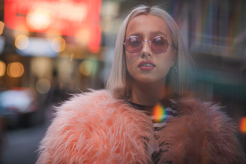 Blond girl in fashionable sunglasses and leather jacket with neon lights