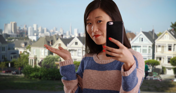 Close up of cute woman taking selfie using smartphone camera in San Francisco