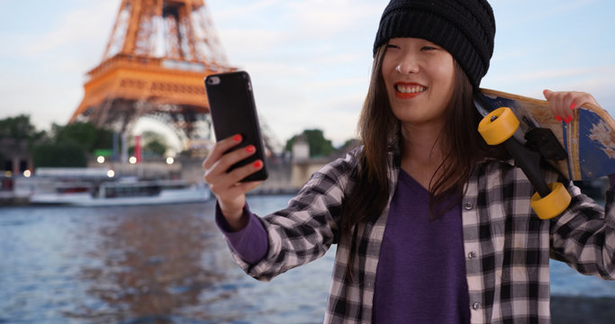 Lovely millennial skater using technology to take selfie in Paris France