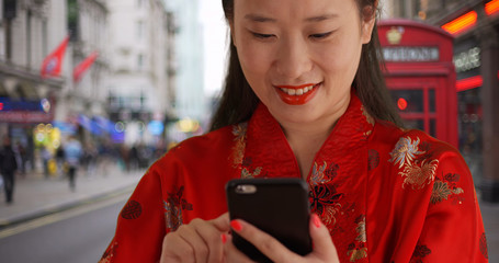 Close up of lovely Asian woman reading on smartphone texts in London UK