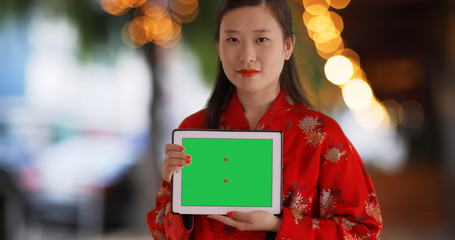 Close up of Chinese woman showing tablet device screen at restaurant outdoors