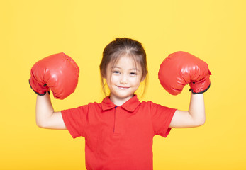 happy little girl with red boxing gloves on yellow background