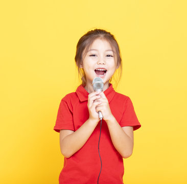 happy little girl singing on yellow background